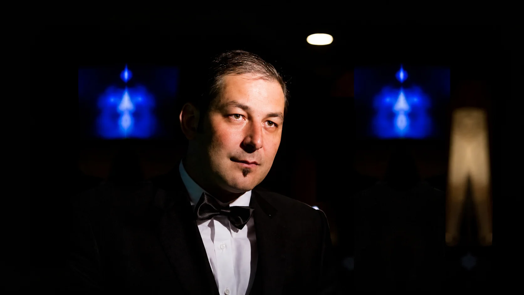 Sorin Mihailovici in a tuxedo, lit against a cinematic dark backdrop